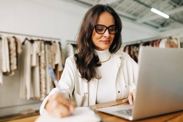 Female business owner taking notes at her laptop.