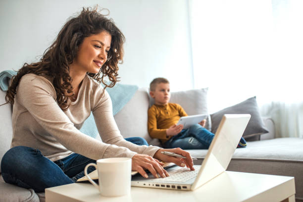 Parent working from home with child sitting close by on half term break.